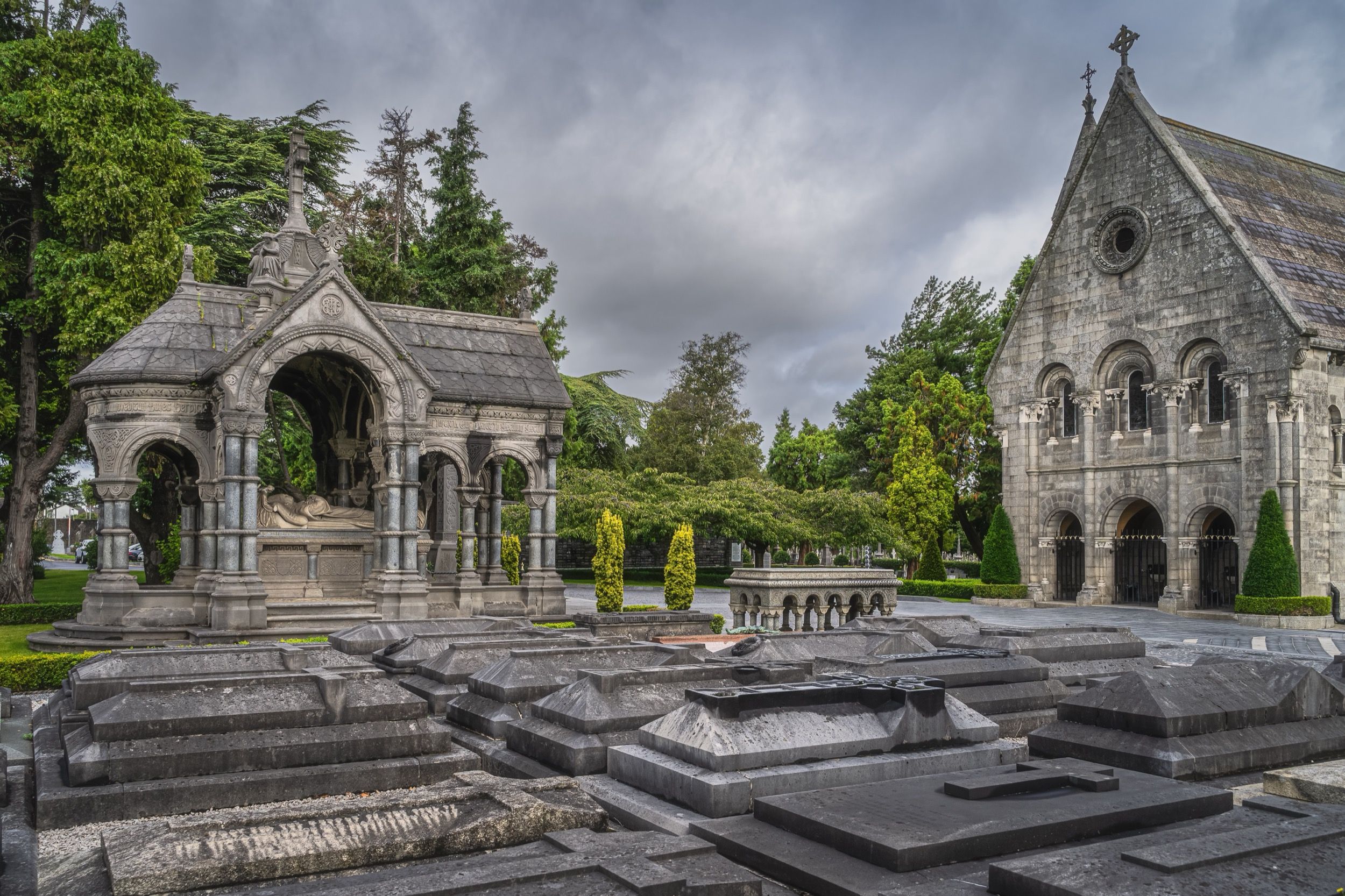 Friedhof mit charakteristischem keltischem Kreuz und weiteren Grabmalen im Hintergrund.