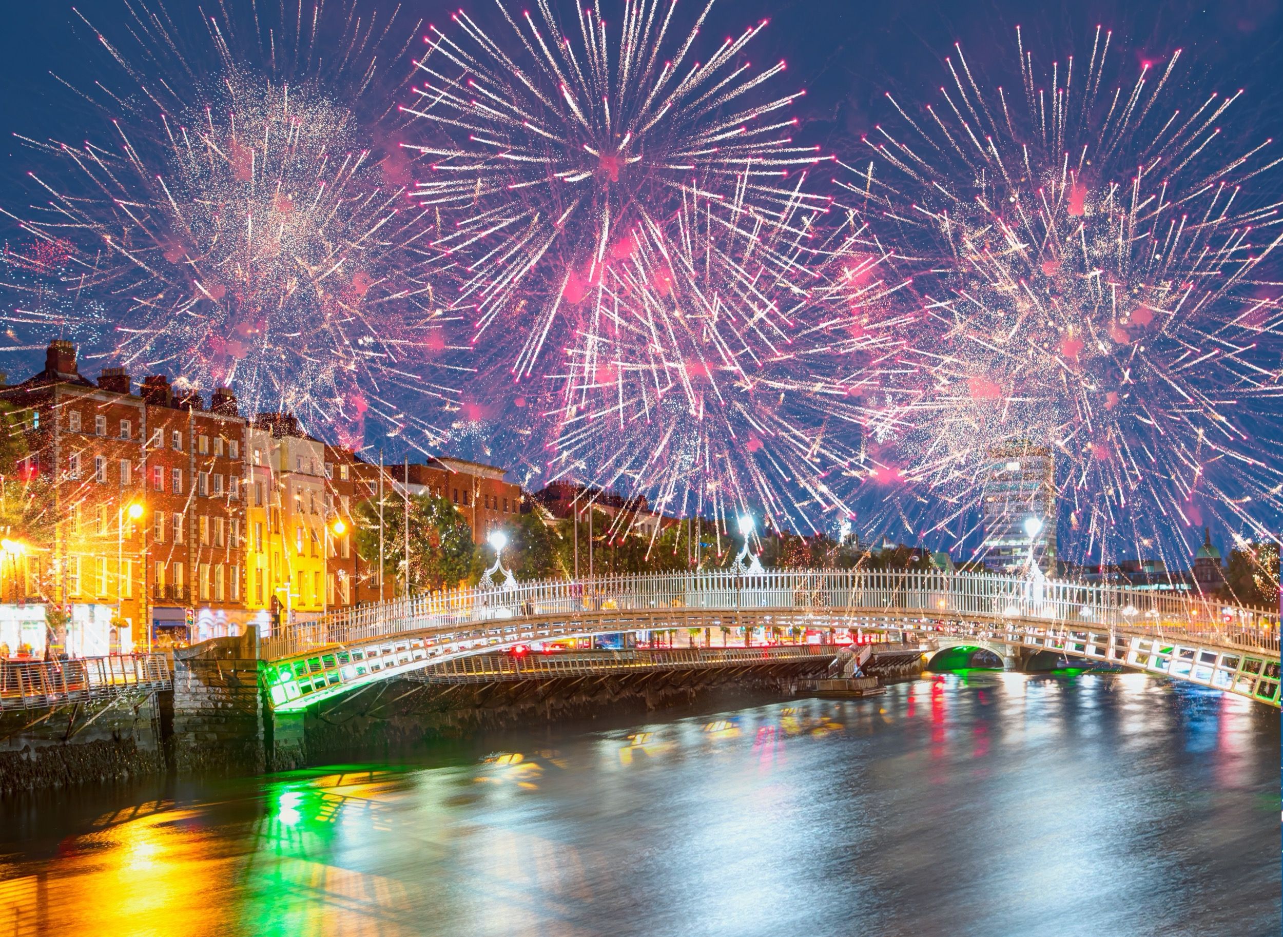 Feuerwerk ueber der Ha'penny Bridge und dem Fluss Liffey bei Nacht.
