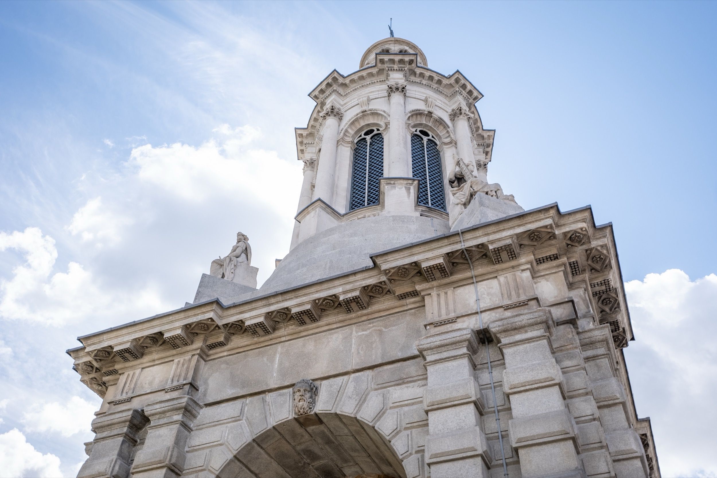 Trinity College Campanile-Turm in der Mitte des Innenhofs mit charakteristischer Glockenturmarchitektur, Touristen und Grünflächen ringsum.