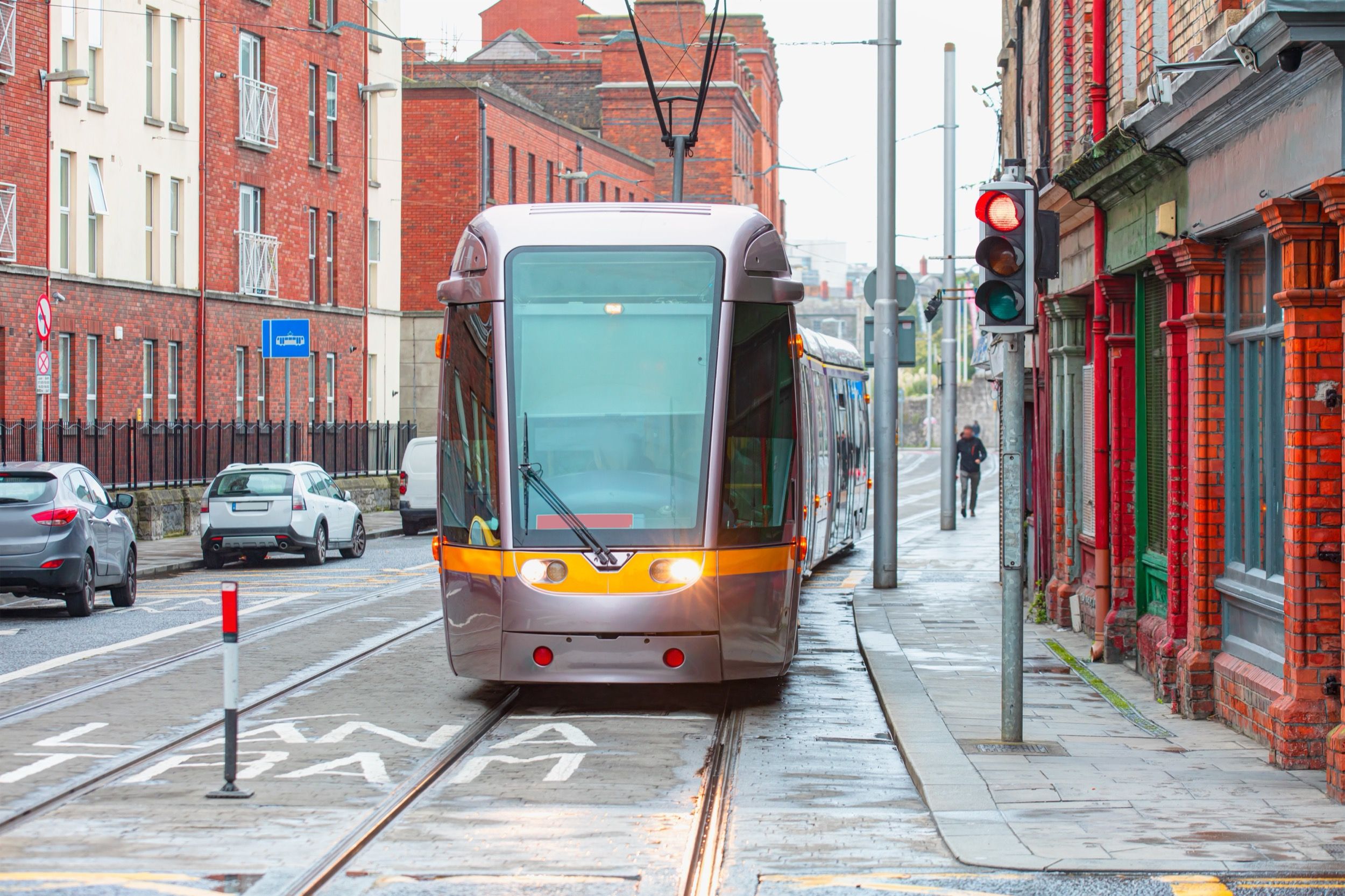 Luas Straßenbahn in Dublin mit roten Backsteingebäuden und urbaner Infrastruktur.