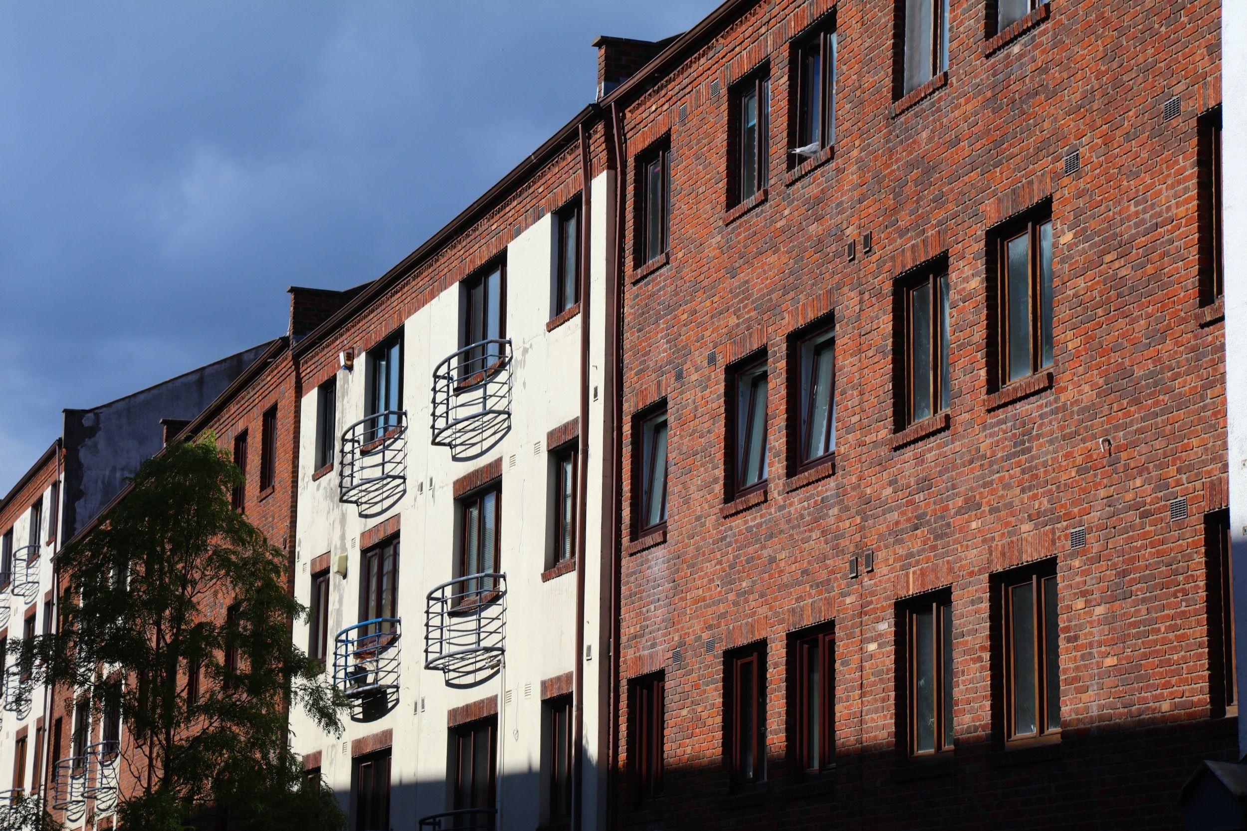 Rote Backstein-Wohngebäude mit kleinen Balkonen im historischen Dubliner Viertel The Liberties unter dramatisch bewölktem Himmel.